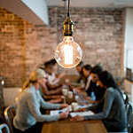 Group of business people brainstorming at a creative office and a light bulb in the foreground.