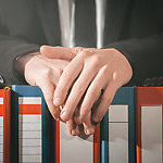 Hands placed atop a row of ring binders.