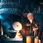 Old Chinese senior man cooking water in simple kitchen. 