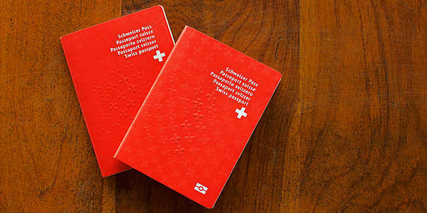 Top view of two Swiss Passports on a wooden table.