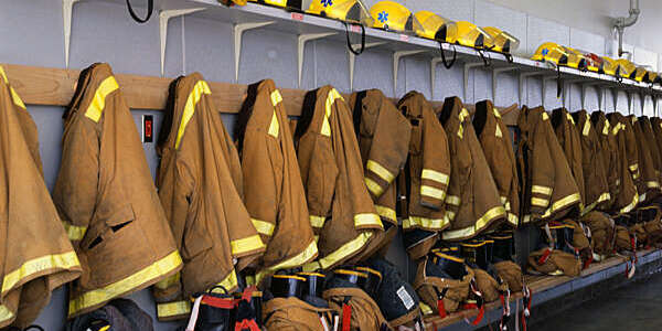 A row of firefighters' helmets, coats, and boots in suspendered pants hang at the ready at a fire station in Oak Harbor.